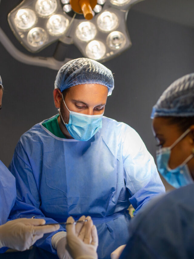 Surgical team performing surgery in modern operation theater,Team of doctors concentrating on a patient during a surgery,Team of doctors working together during a surgery in operating room,